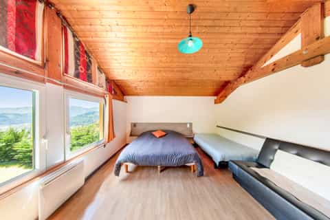 Chambre vue vallée du gîte Jonquille, plafond bois et grande fenêtre panoramique sur les Vosges
