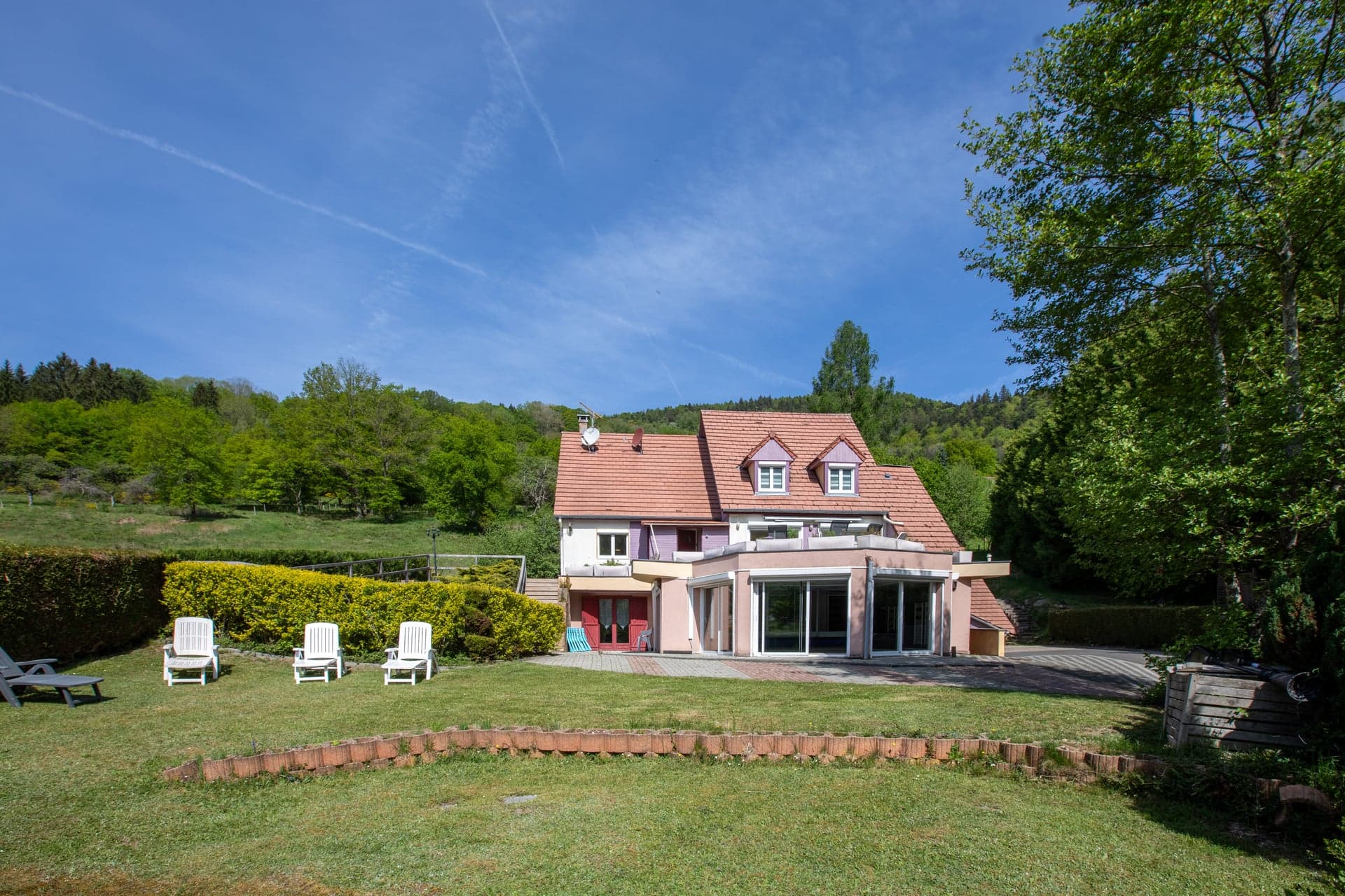 Façade arrière du gîte Gentiane vue du jardin avec verrière panoramique et transats (gîte groupe 15 personnes, vallée de la Thur, Alsace)