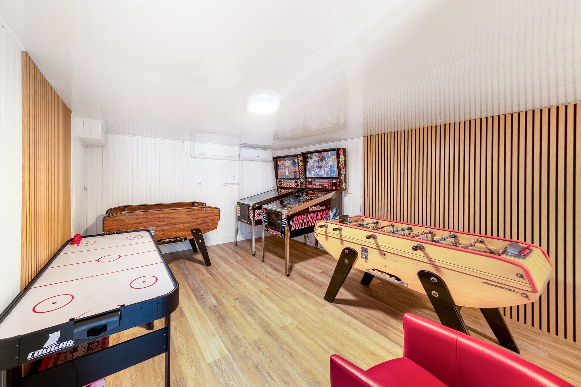 Salle de jeux du gîte Gentiane avec babyfoot, flipper et air hockey, mur acoustique en lattes bois (gîte groupe famille Hautes-Vosges)