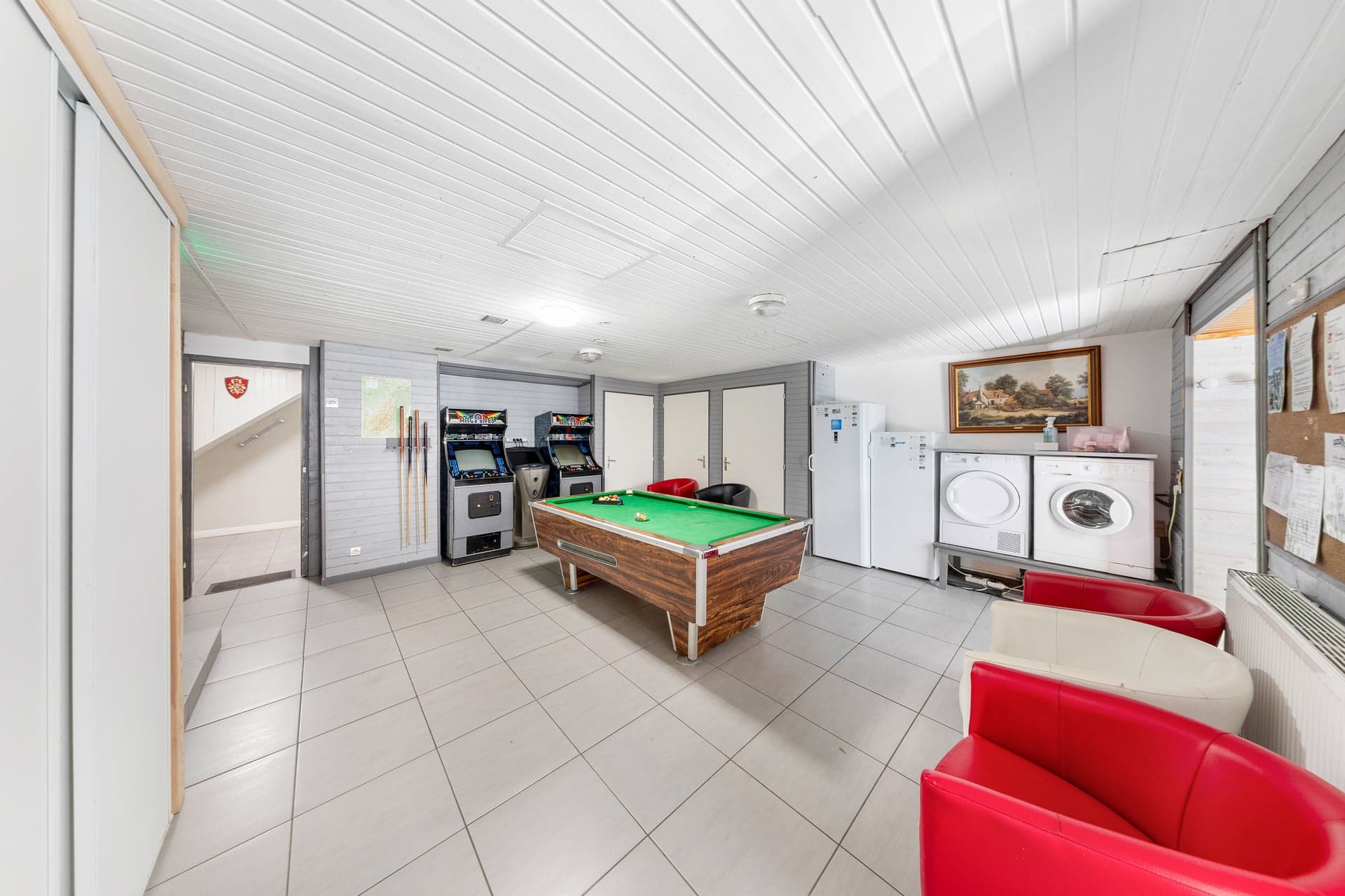 Salle de jeux du gîte Gentiane avec billard, bornes d'arcade rétro et coin buanderie (gîte groupe famille 15 personnes, Alsace)