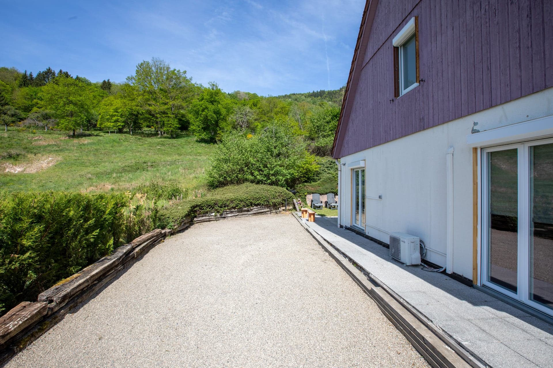 Terrasse arrière en gravillons du gîte Gentiane ouverte sur prairie et forêt (gîte groupe Saint-Amarin, Alsace)