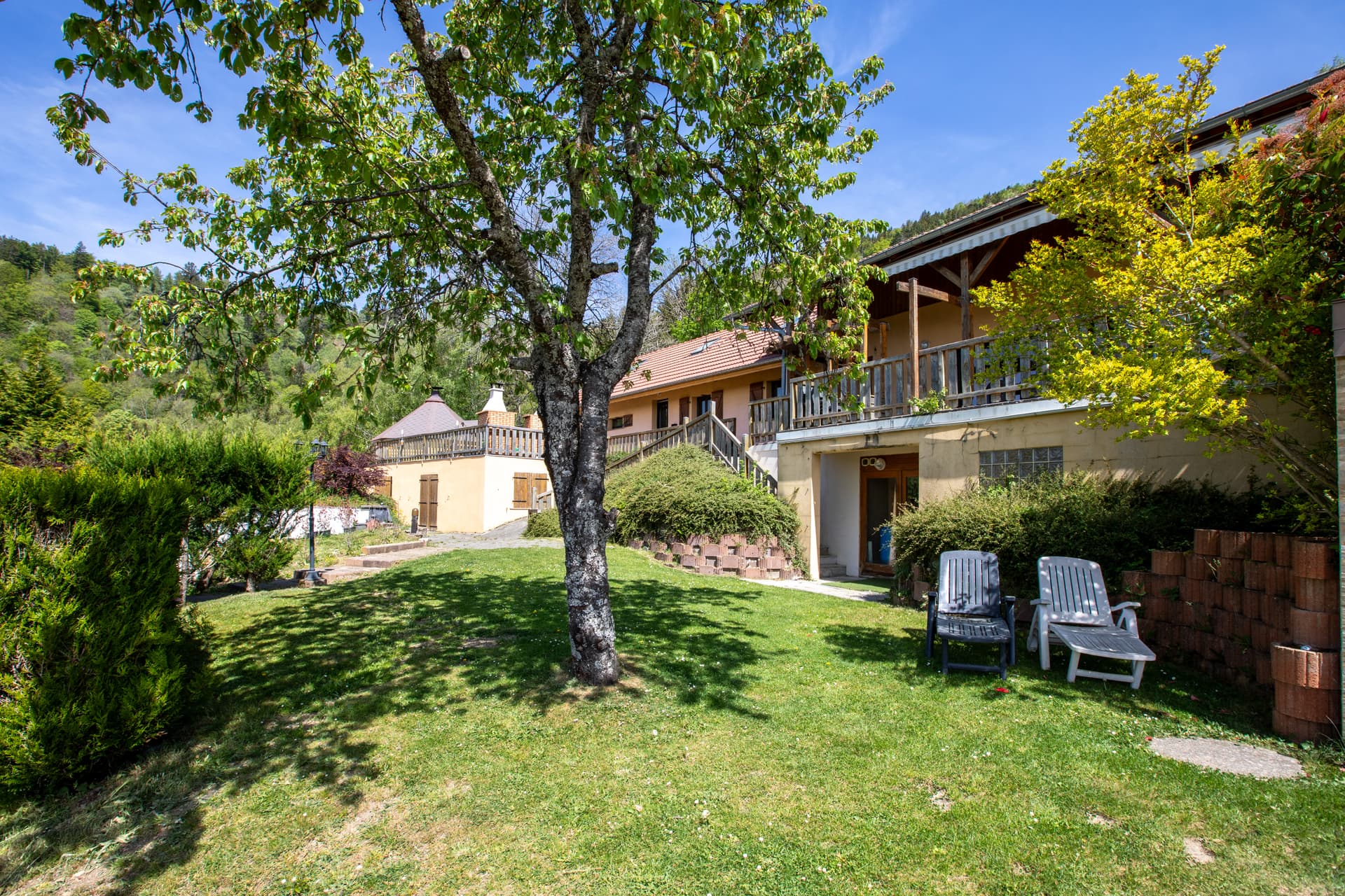 Façade côté jardin du gîte Jonquille avec arbres et pelouse