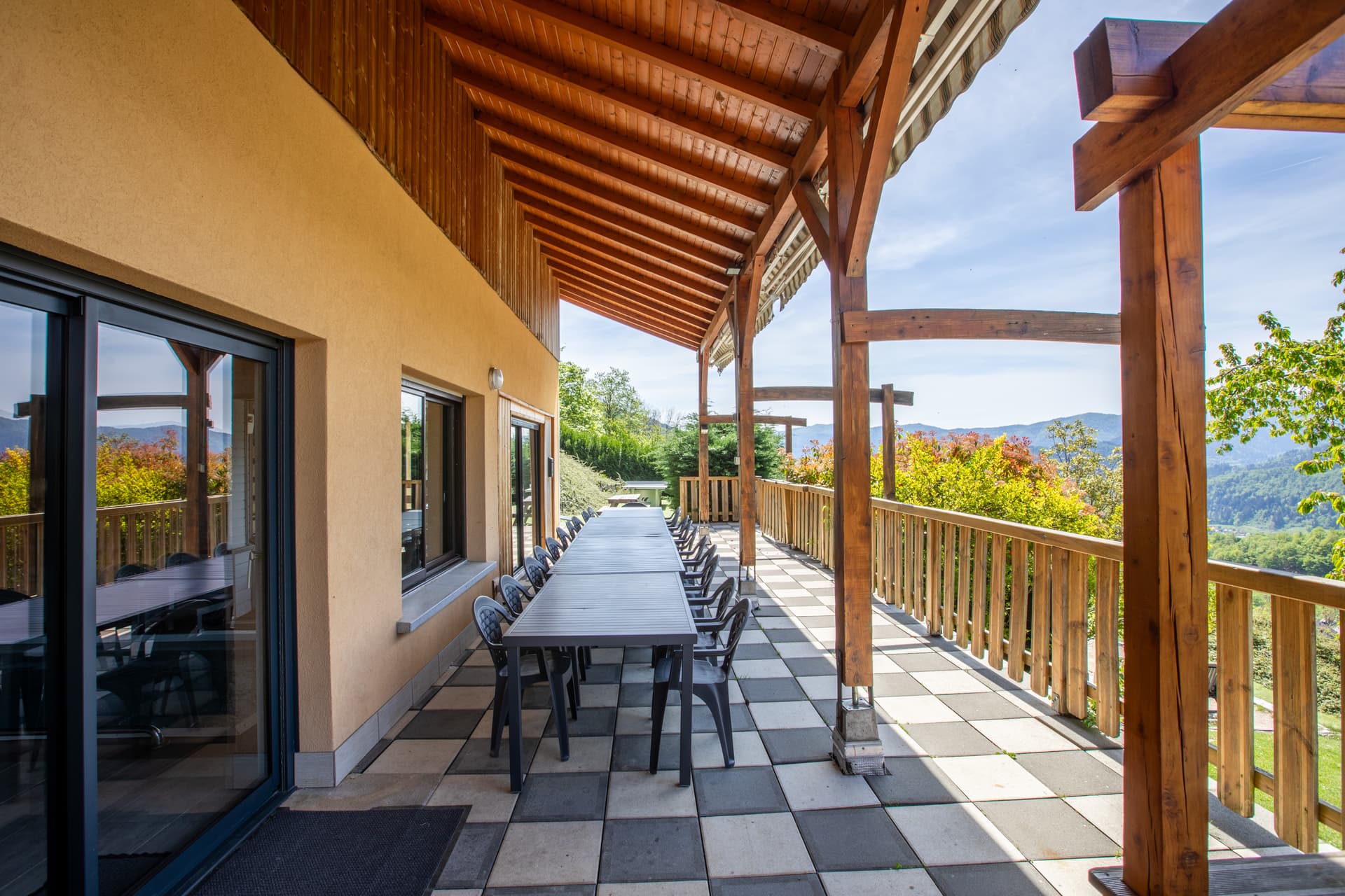 Grande terrasse couverte du gîte Jonquille avec longue table sous pergola